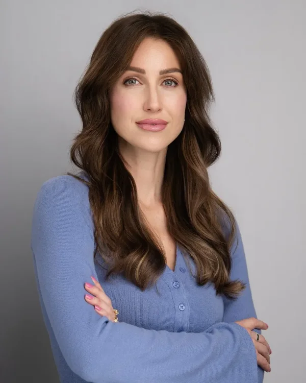 Studio headshot of a woman in a blue cardigan on a grey backdrop at the Langley studio