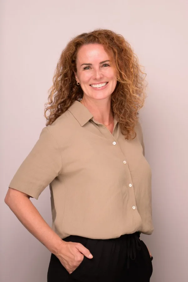 Personal branding headshot of Melanie Huck photographed on a soft pink backdrop
