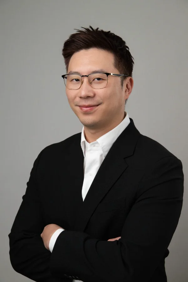 Professional headshot of Jae Han on a dark studio backdrop