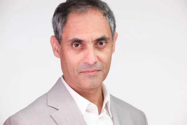 Professional headshot of Saqib Khan on a light grey studio backdrop