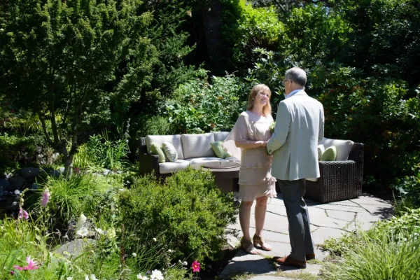 Intimate garden wedding ceremony with the couple exchanging vows on a stone path surrounded by flowers