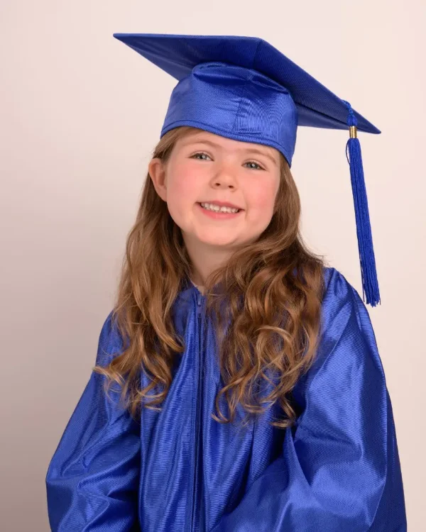 A preschool graduate in a royal blue cap and gown