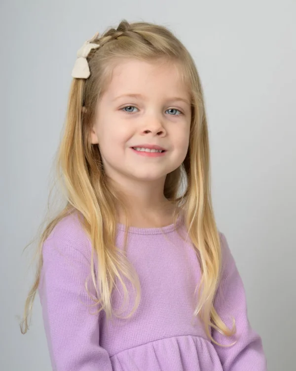 A girl in a lilac knit top on a soft grey backdrop
