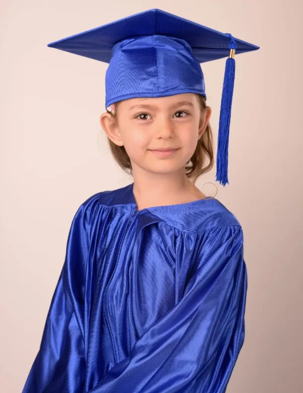 A preschool graduate in a royal blue cap and gown
