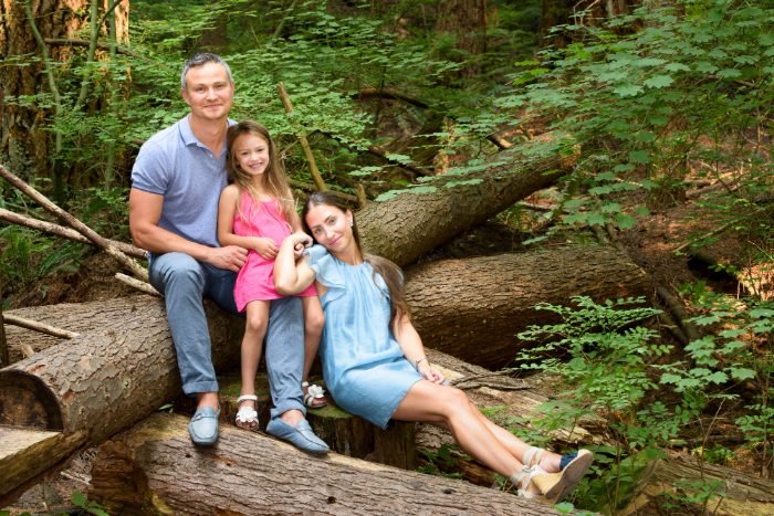 A family photographed on a fallen log in a Langley forest