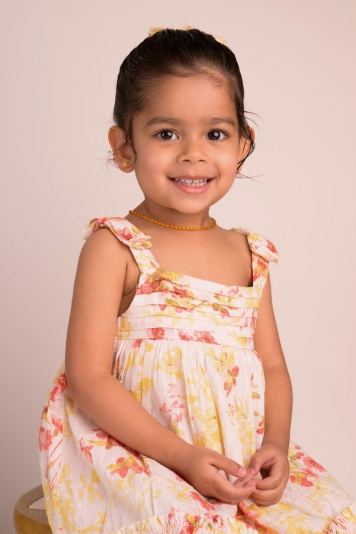 Preschool portrait of a girl in a floral sundress on a warm-neutral studio backdrop