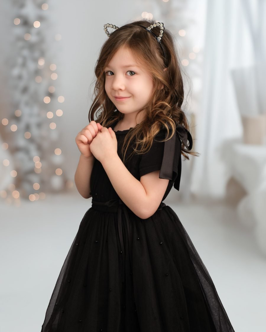 Girl in a black tulle dress and sparkly cat-ear headband at her holiday photo session