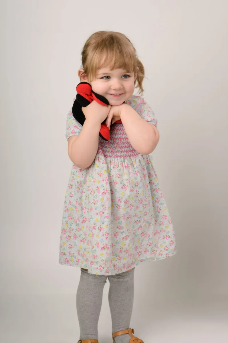 The same toddler standing and holding the felt hat at the end of her session