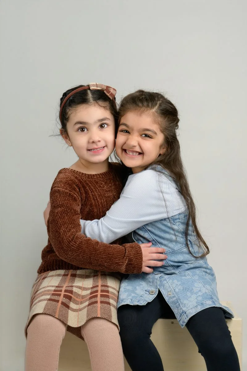 Two girls in a tight hug, both beaming at the camera