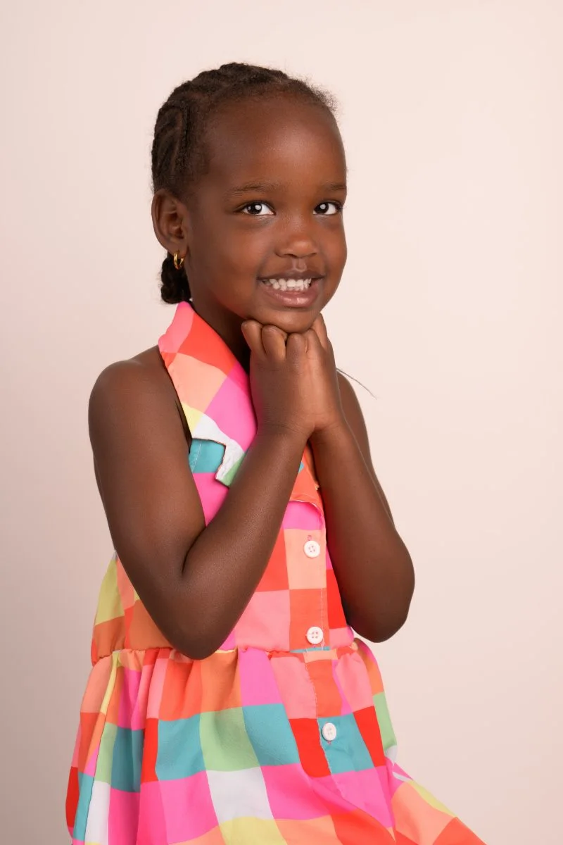 The same girl with a hand under her chin, grinning