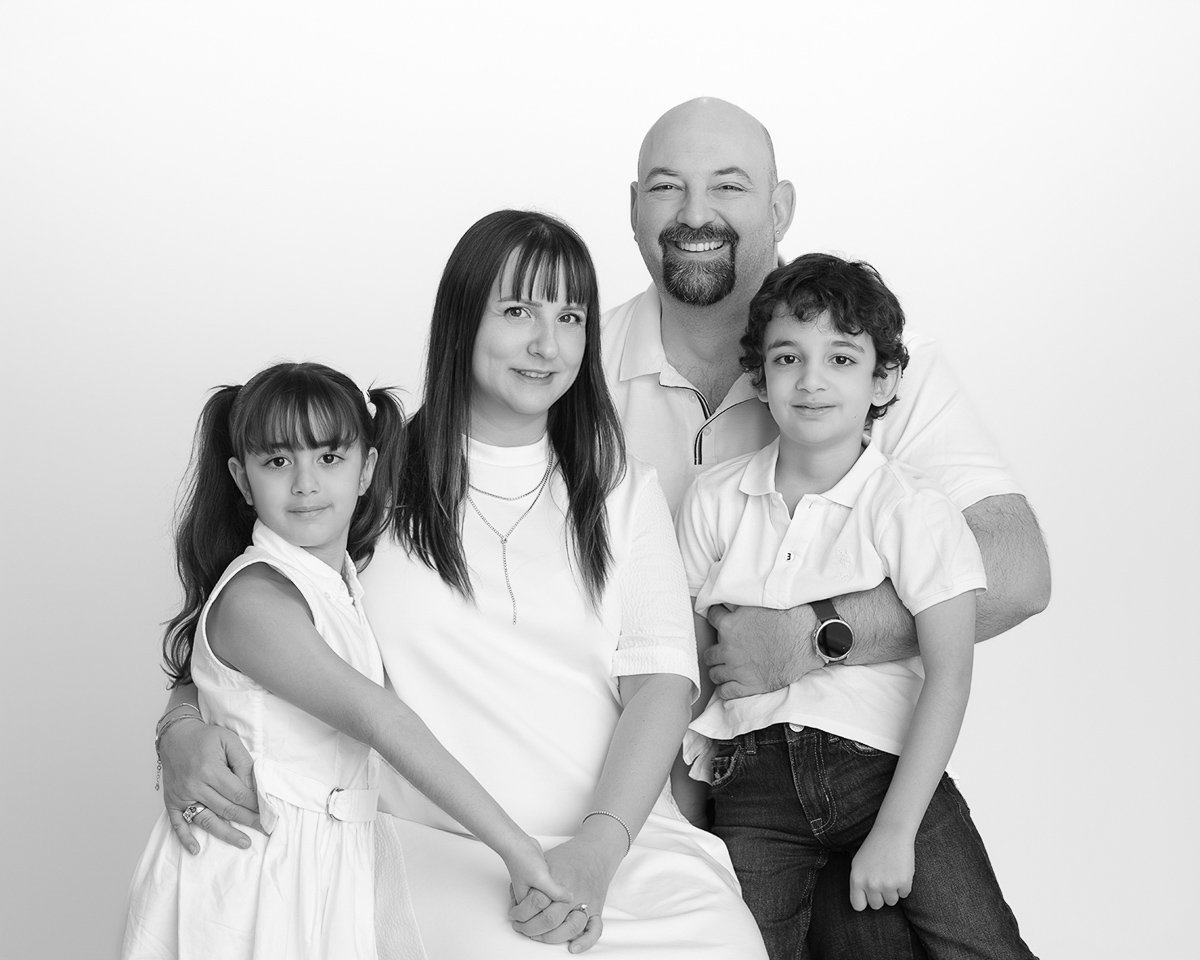 Family of four portrait in black and white on a white studio backdrop during a mini session