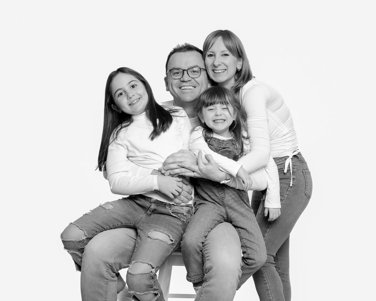 Family of four laughing together in black and white during a studio mini session