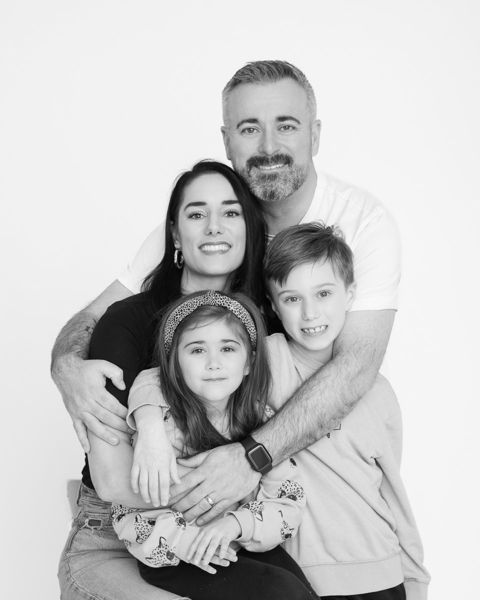 Family of four embracing in black and white during a studio mini session