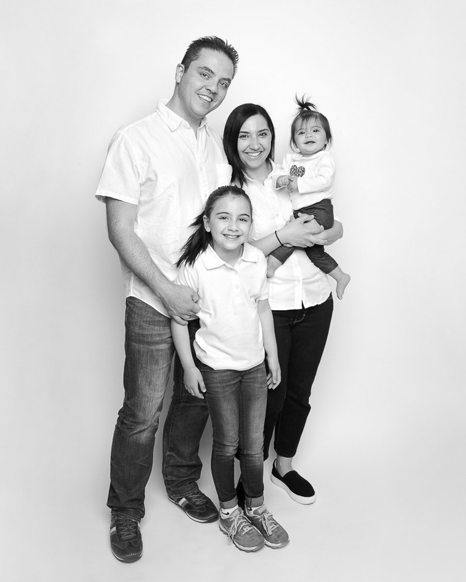 Family of four standing together in black and white during a studio mini session