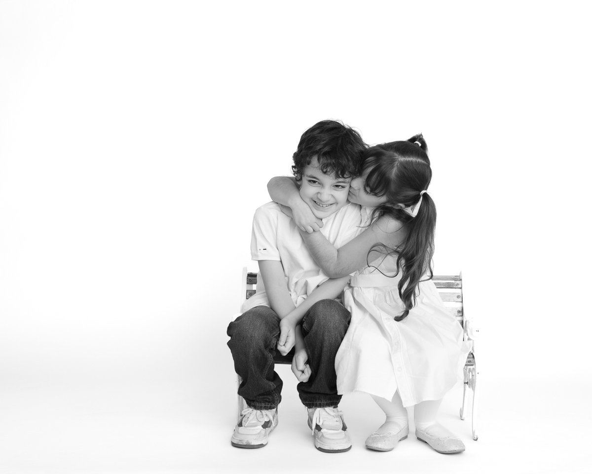 Brother and sister hugging on a bench in black and white during a studio mini session