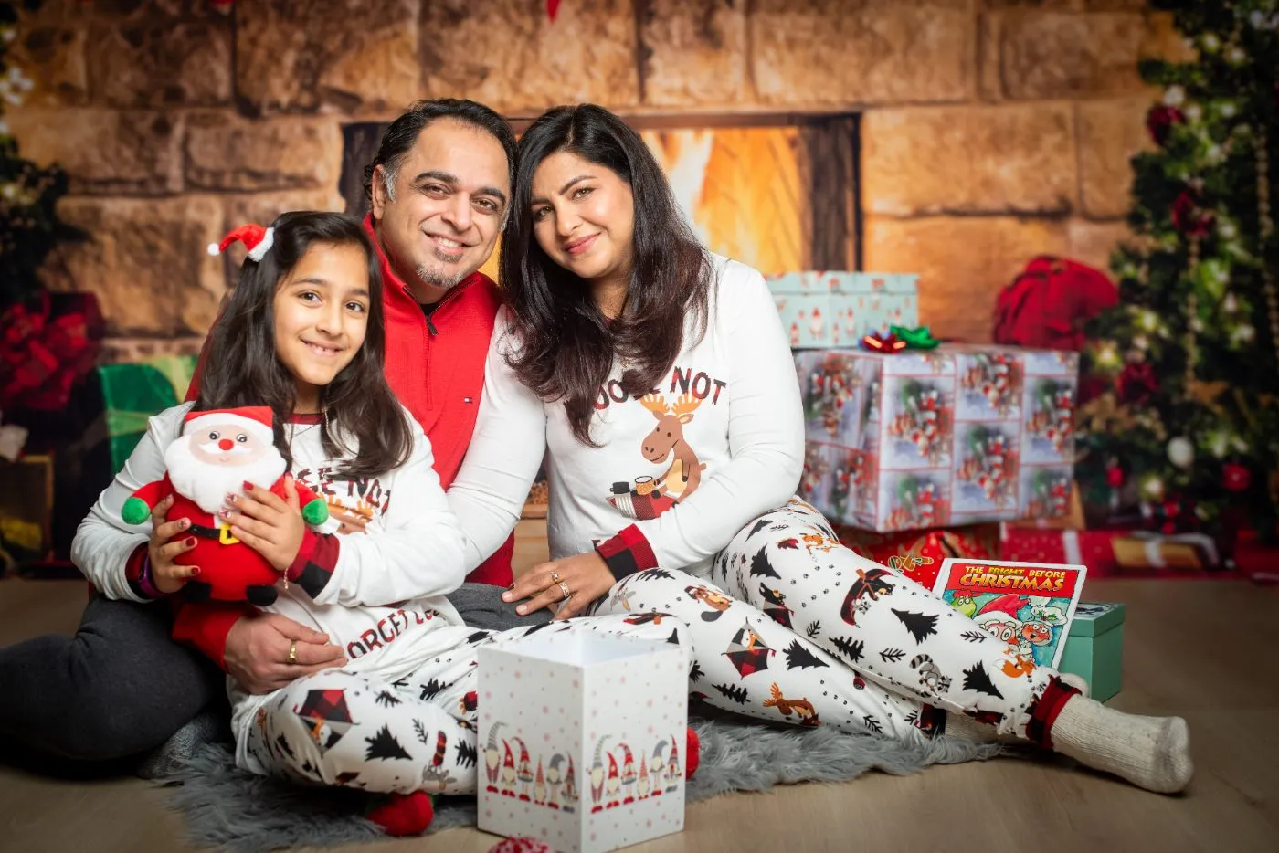 Family of three in matching holiday pyjamas on the fireplace set during a Christmas mini session