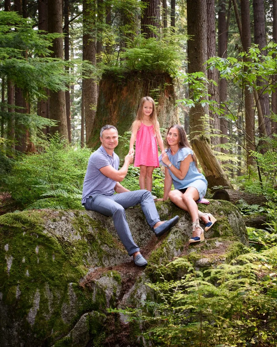 Parents and their daughter on a mossy boulder in an old growth forest during an outdoor family session