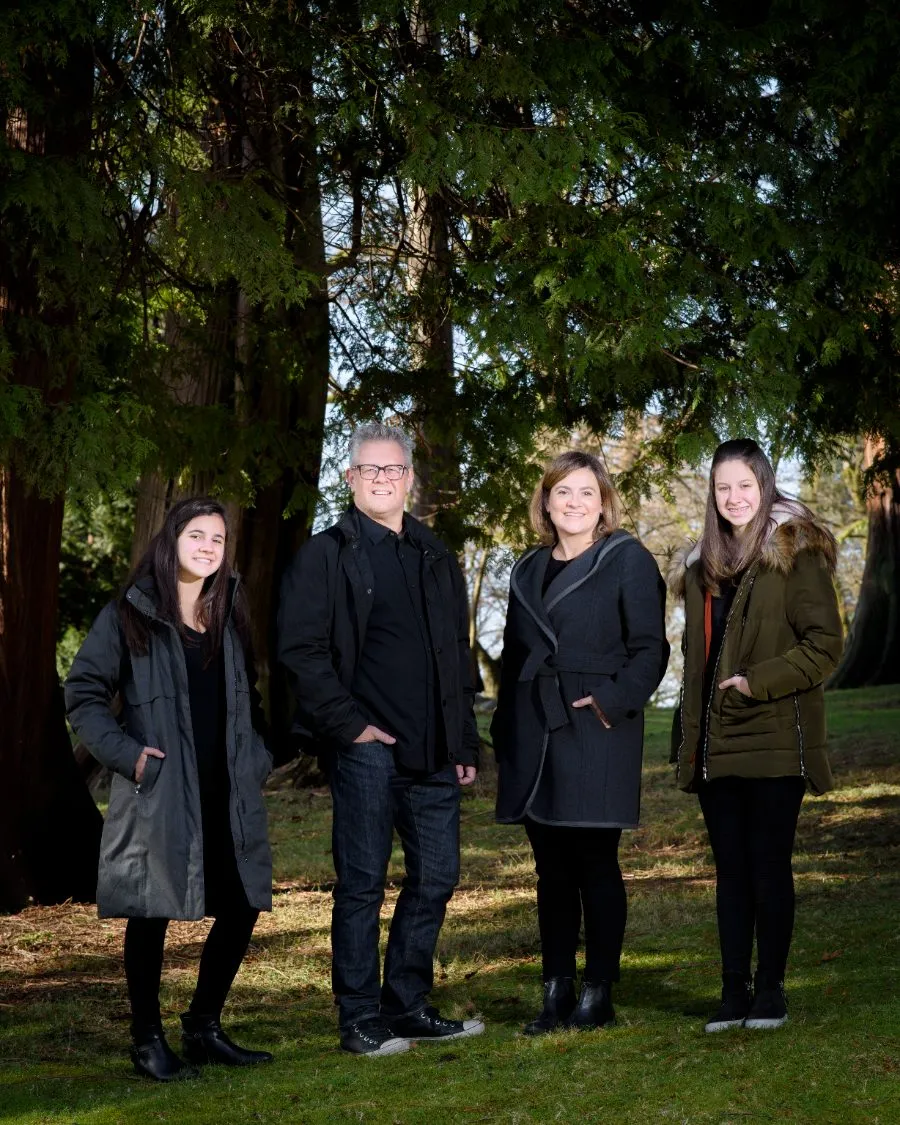 Family of four standing under tall cedar trees during an outdoor family session