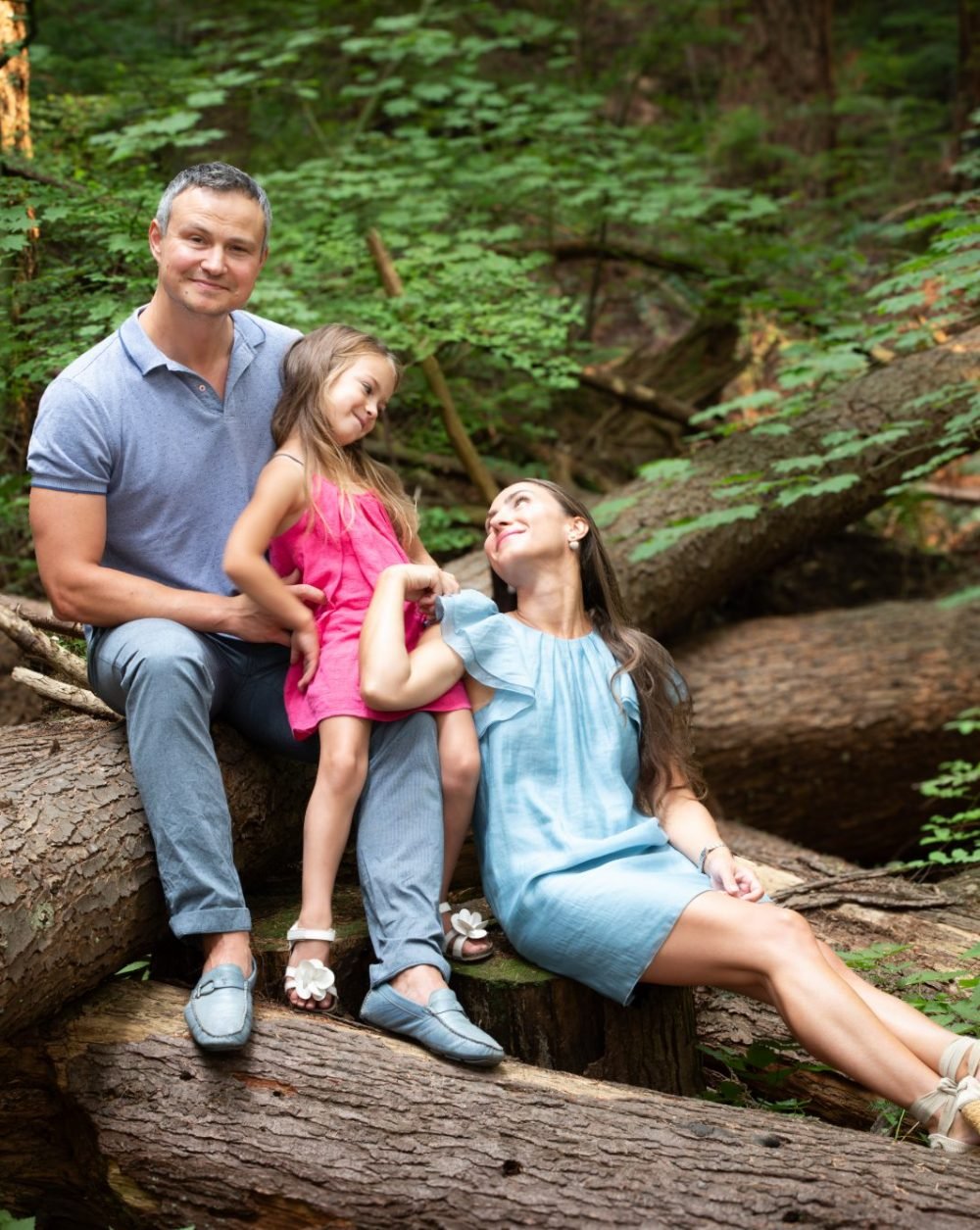 Family sitting on a fallen log during a forest session