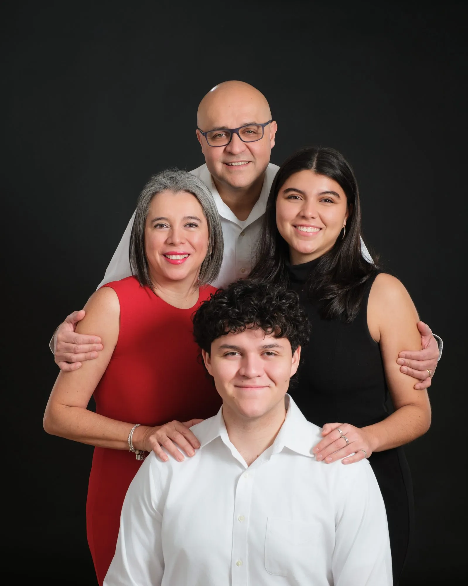 Family of four photographed on a black studio backdrop