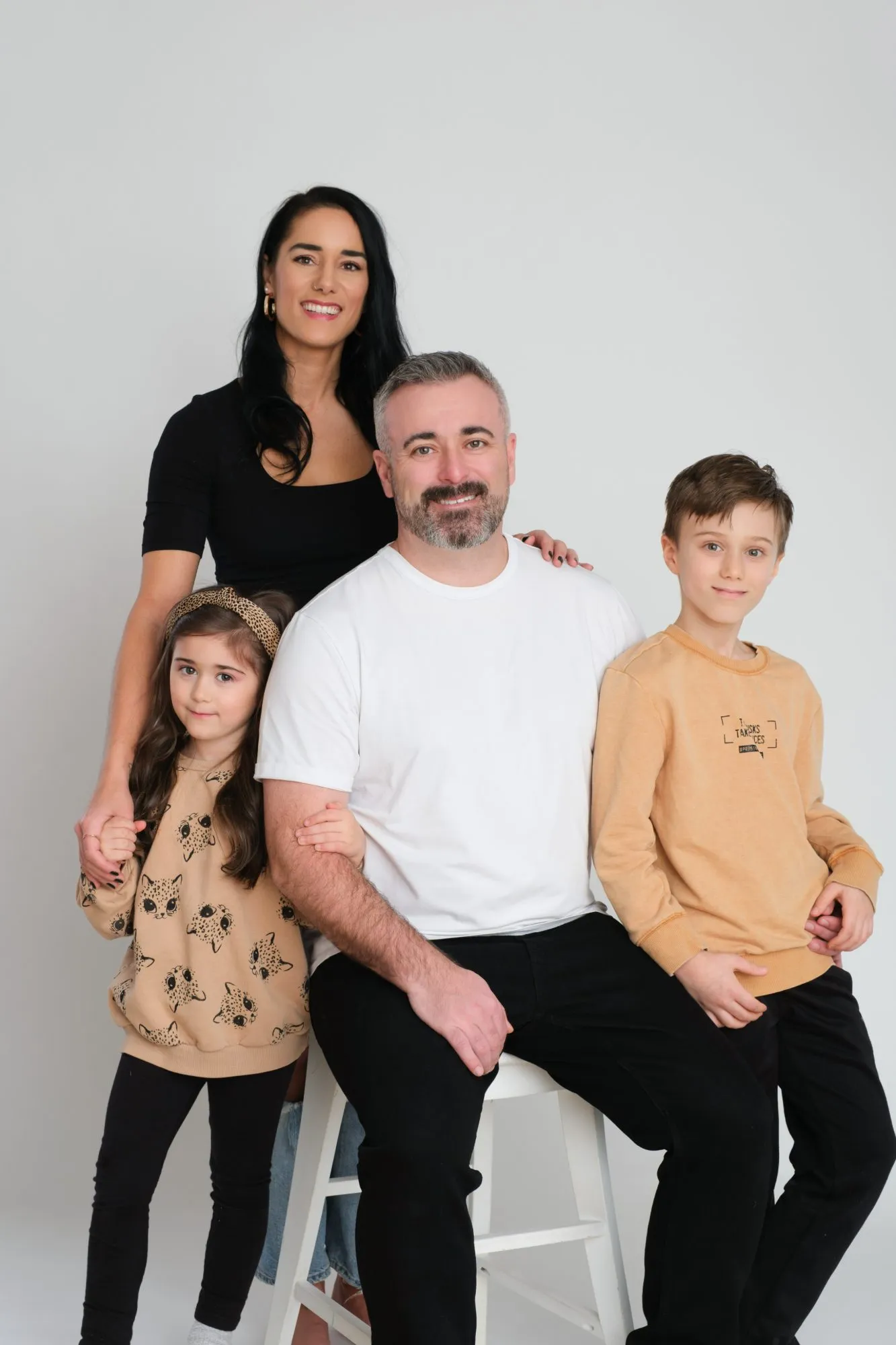 Family of four gathered around a studio stool during a mini session