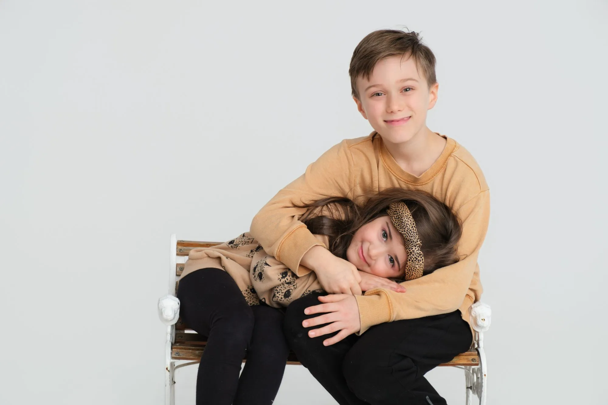 Brother and sister on a studio bench during a family portrait session