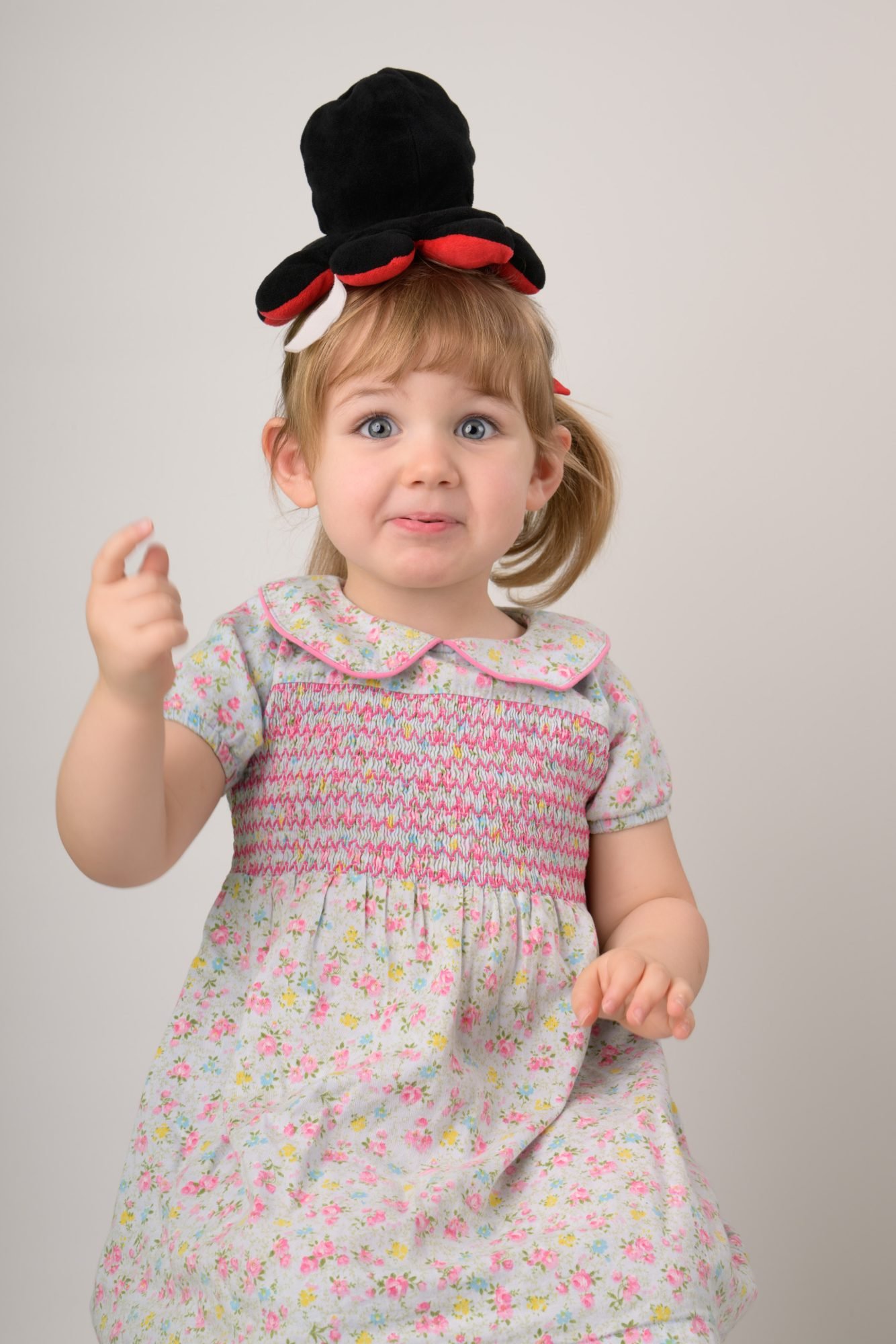The same toddler mid-reaction with the felt hat still balanced on her head