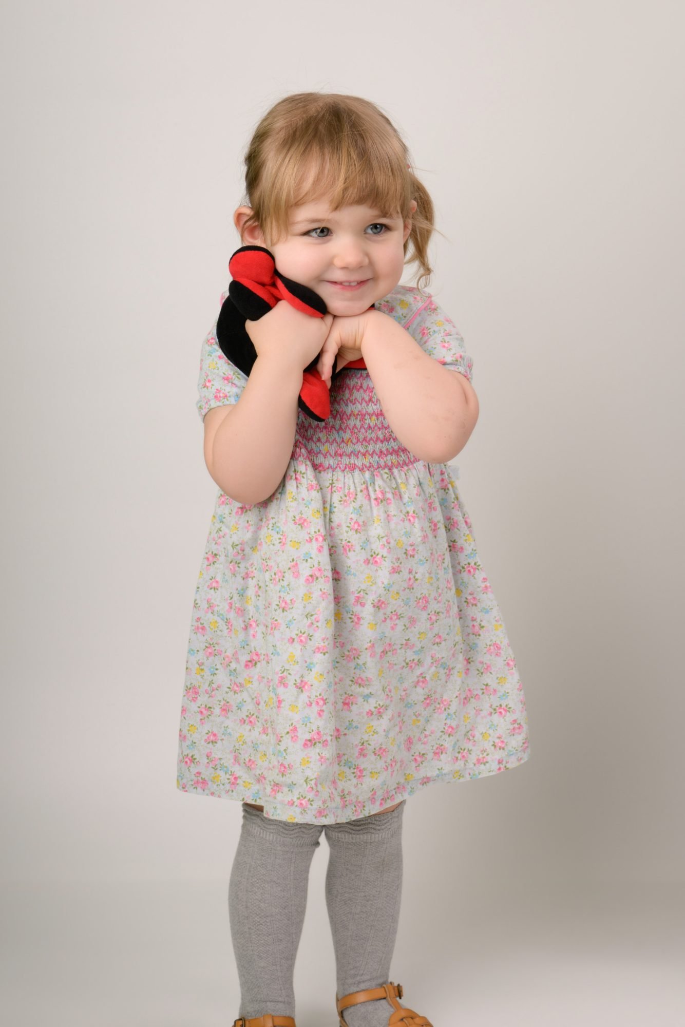 The same toddler standing and holding the felt hat at the end of her session