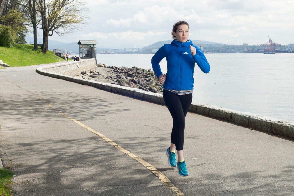Athletic apparel campaign photography of a runner in a blue technical jacket on the Vancouver seawall