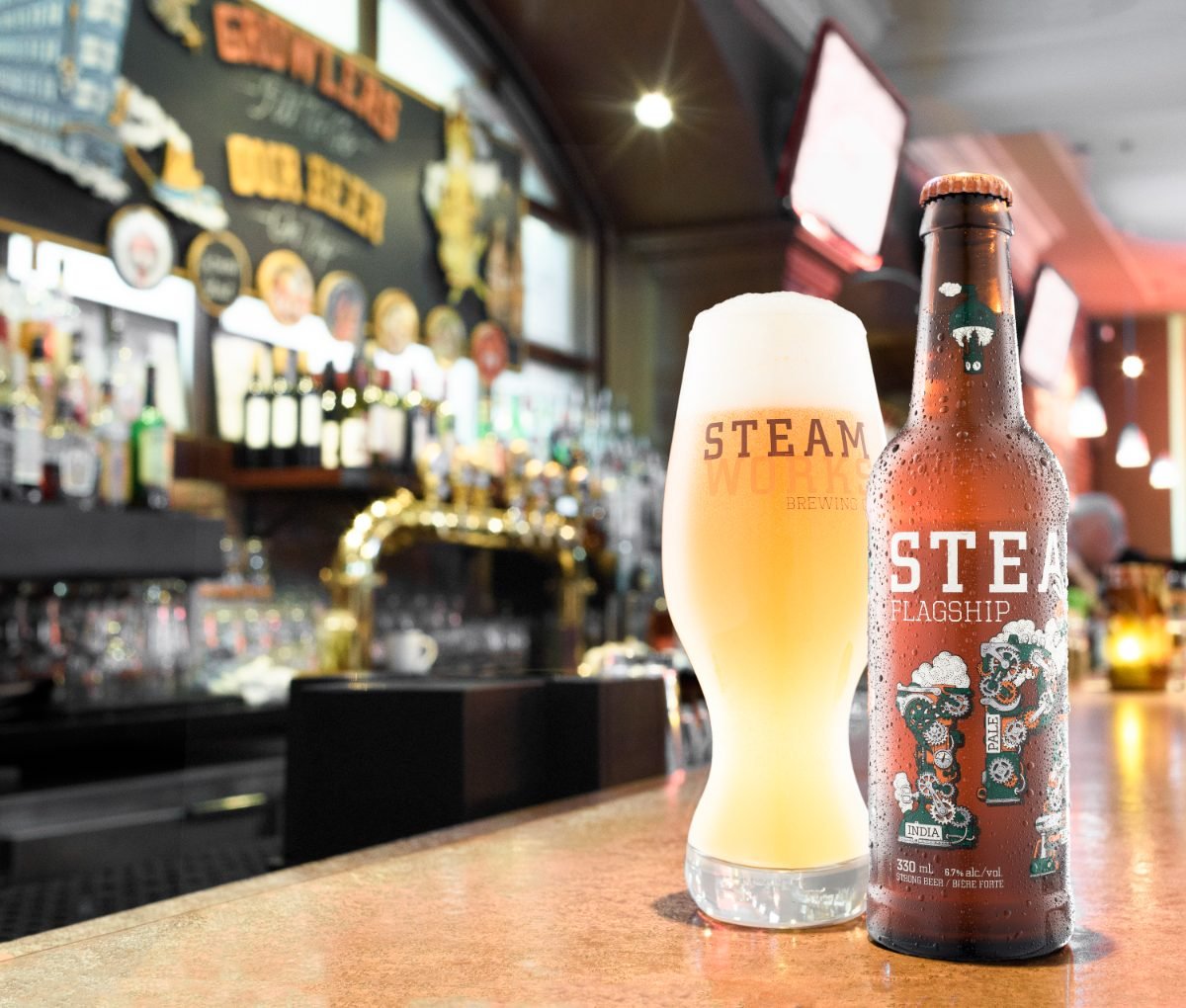 Brewery photography of a craft IPA bottle and full glass on the brass bar of a Vancouver brewpub