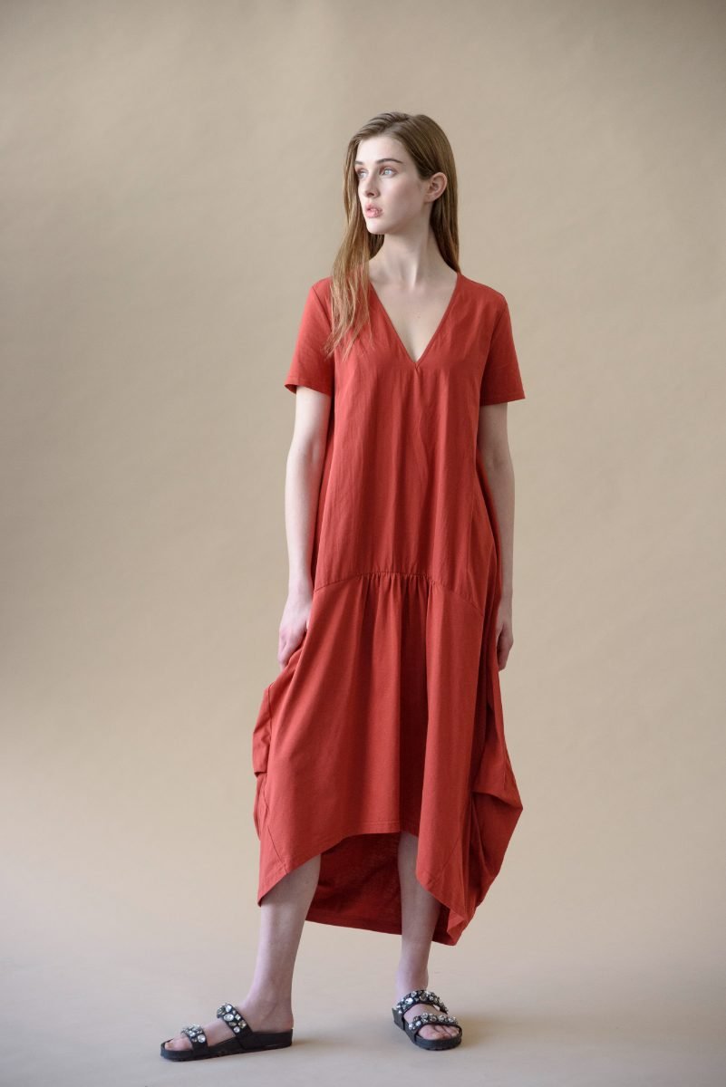 E-commerce clothing photography of a model in a rust cotton midi dress against a neutral studio background