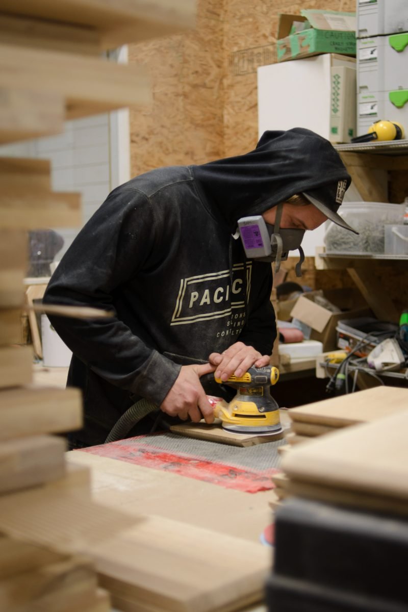 Trades photography of a finishing carpenter sanding a cabinet door in a custom millwork shop
