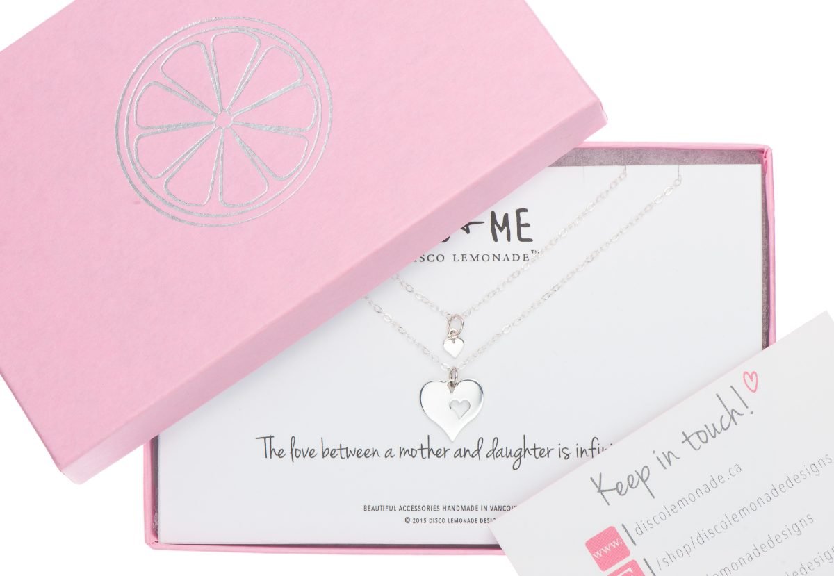 Packaging photography of a mother and daughter necklace set in a pink gift box with a card