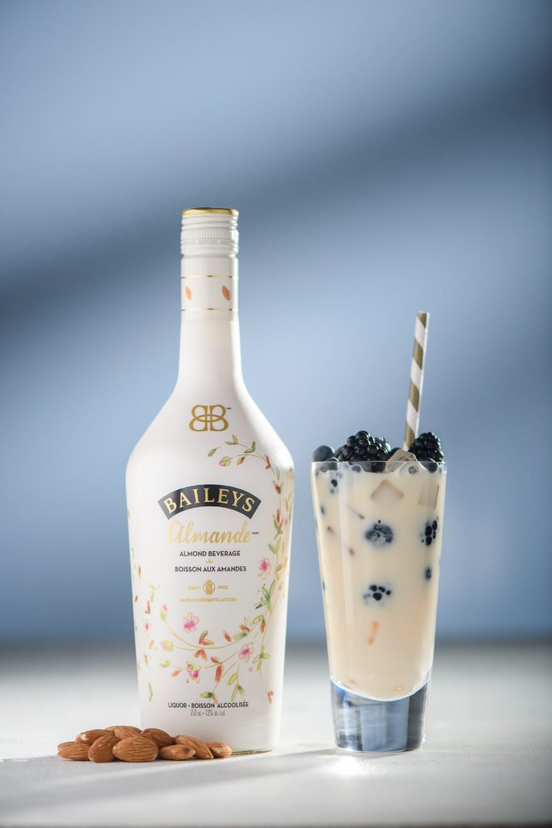 Liqueur product photography of an almond cream bottle with a berry-topped iced drink and almonds