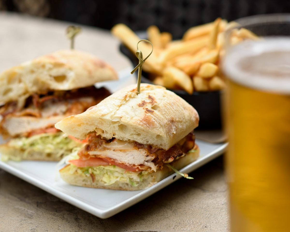 Pub menu photography of a chicken ciabatta sandwich with fries and a cold draught beer