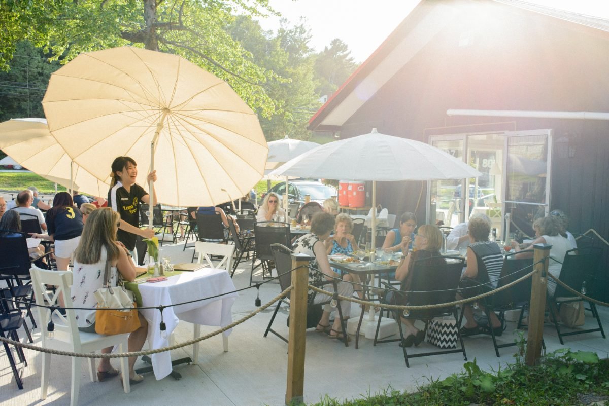Hospitality photography of a full restaurant patio with guests and parasols in golden evening light