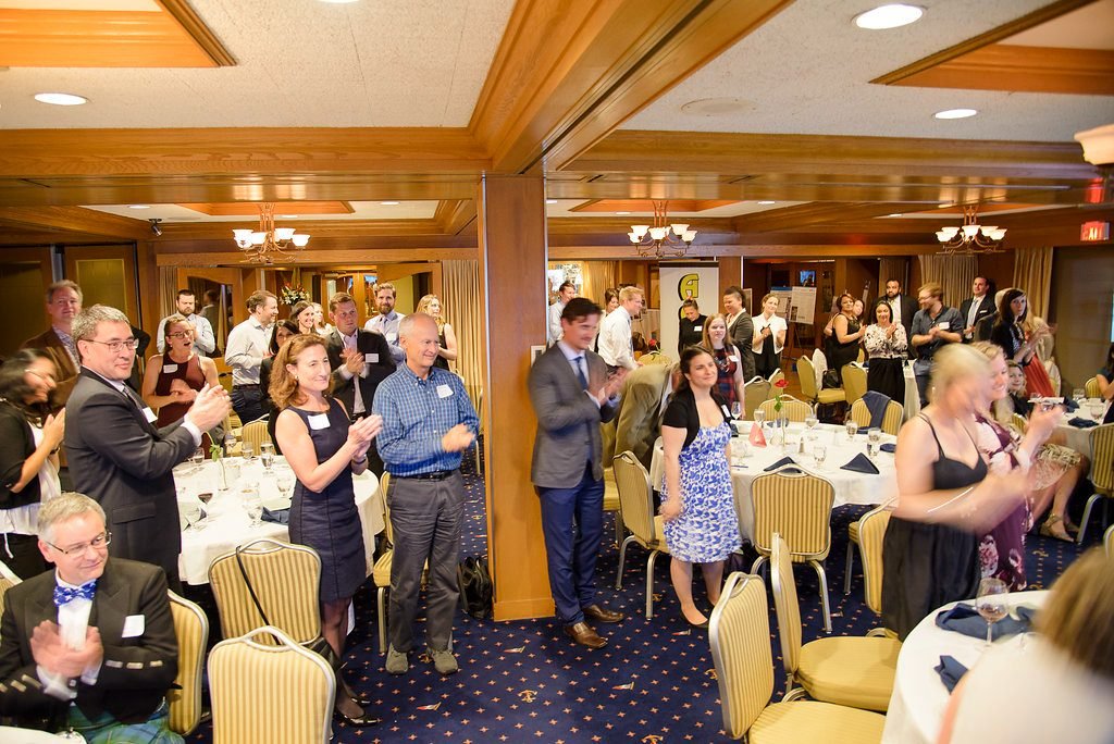 Guests standing and applauding a winner during an association awards banquet in Vancouver