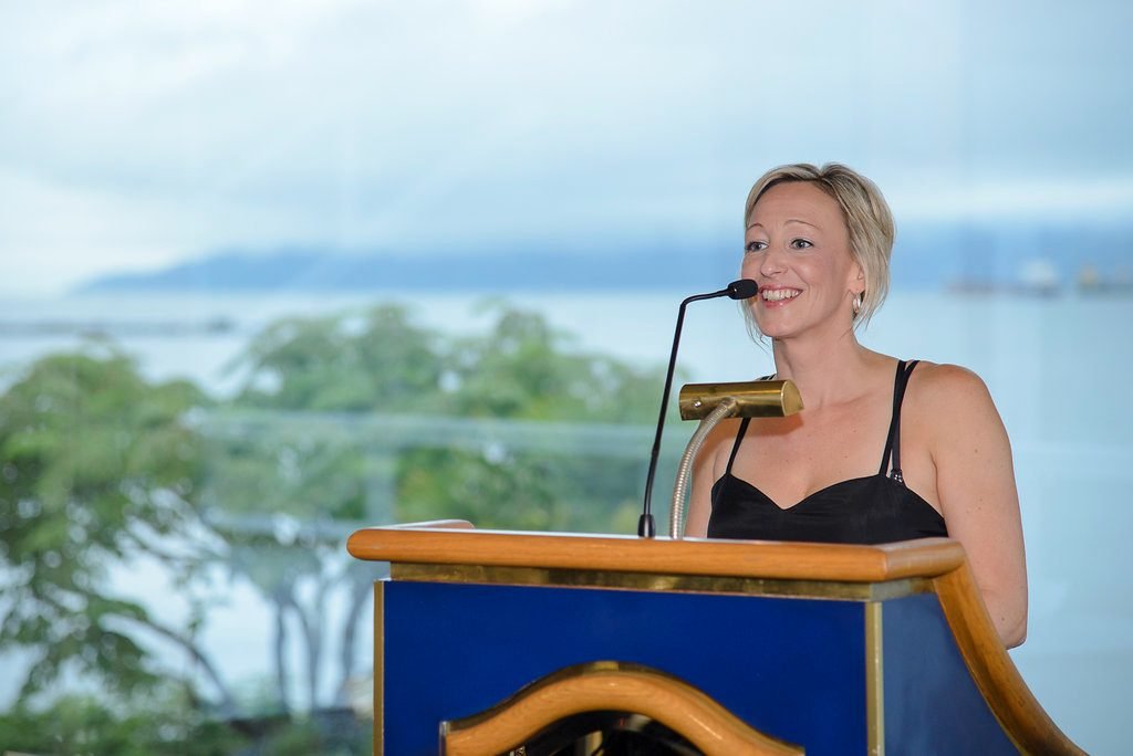 Association director speaking from the podium with the Vancouver waterfront behind her