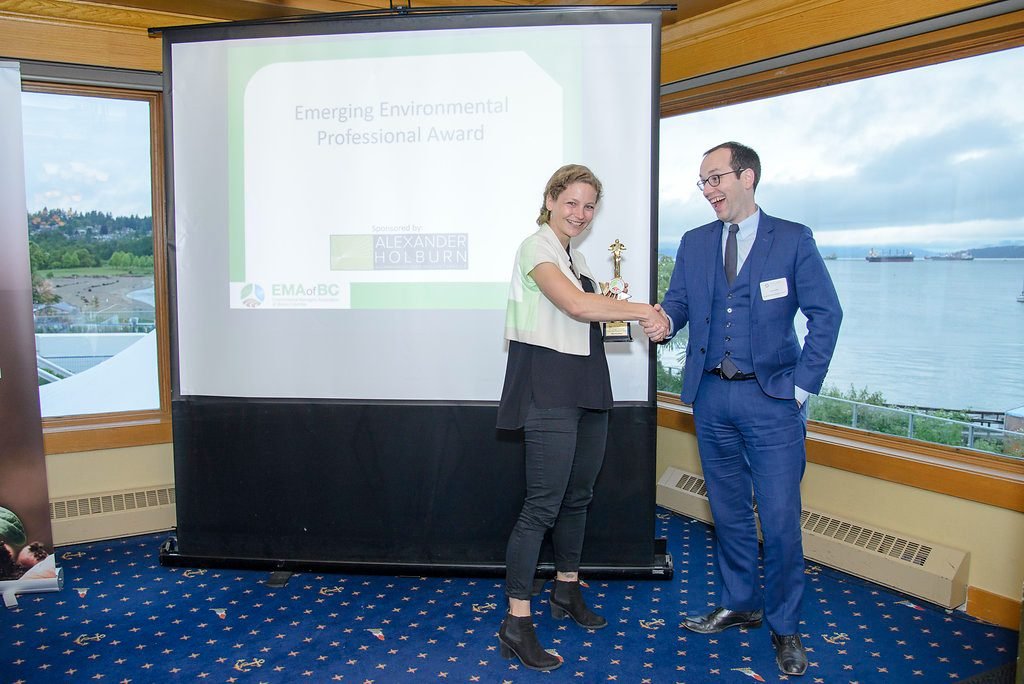 Presenter shaking hands with an award recipient on stage at an environmental industry awards banquet
