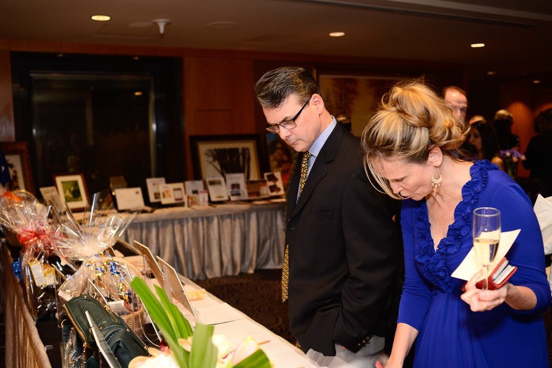 Two guests browsing the silent auction table at a charity fundraising gala