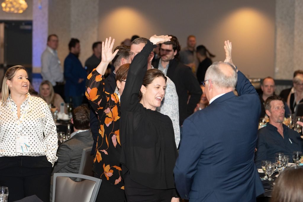 Guests raising their hands to bid during the live auction at a charity gala