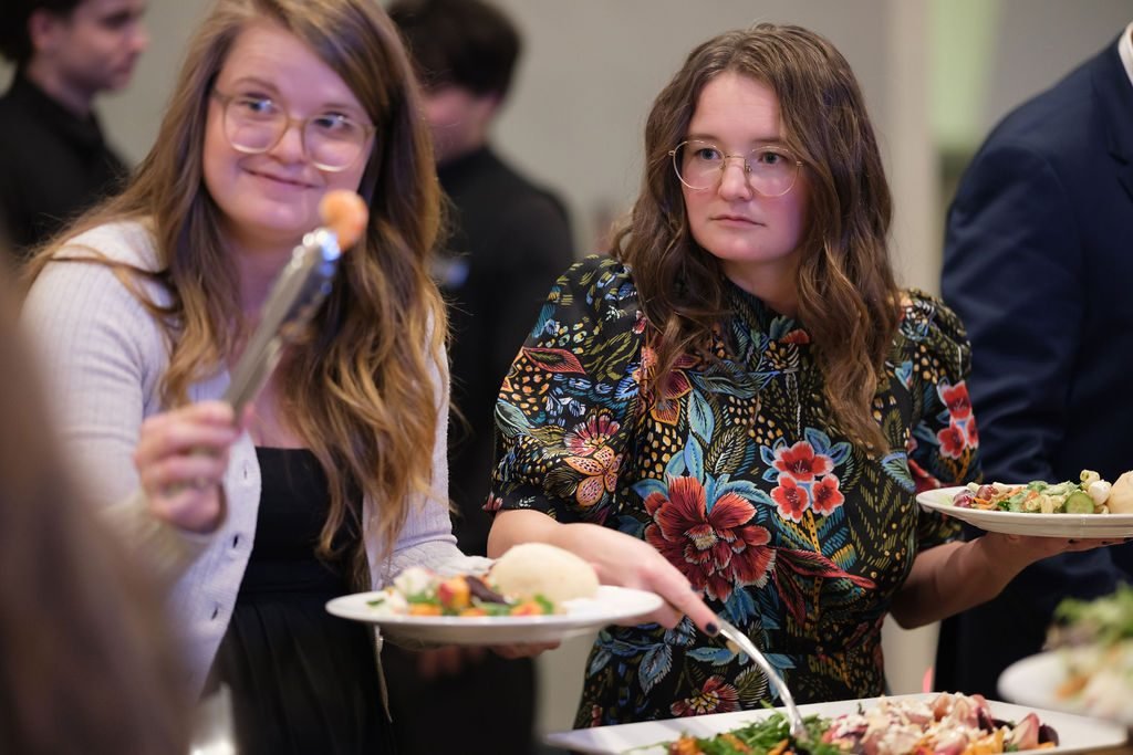 Two guests laughing as they serve themselves at the buffet during a company banquet