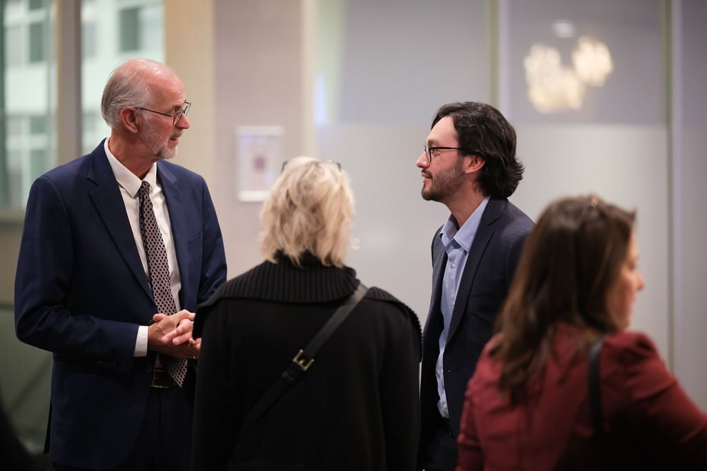 Three guests in business attire talking during a pre-dinner networking reception