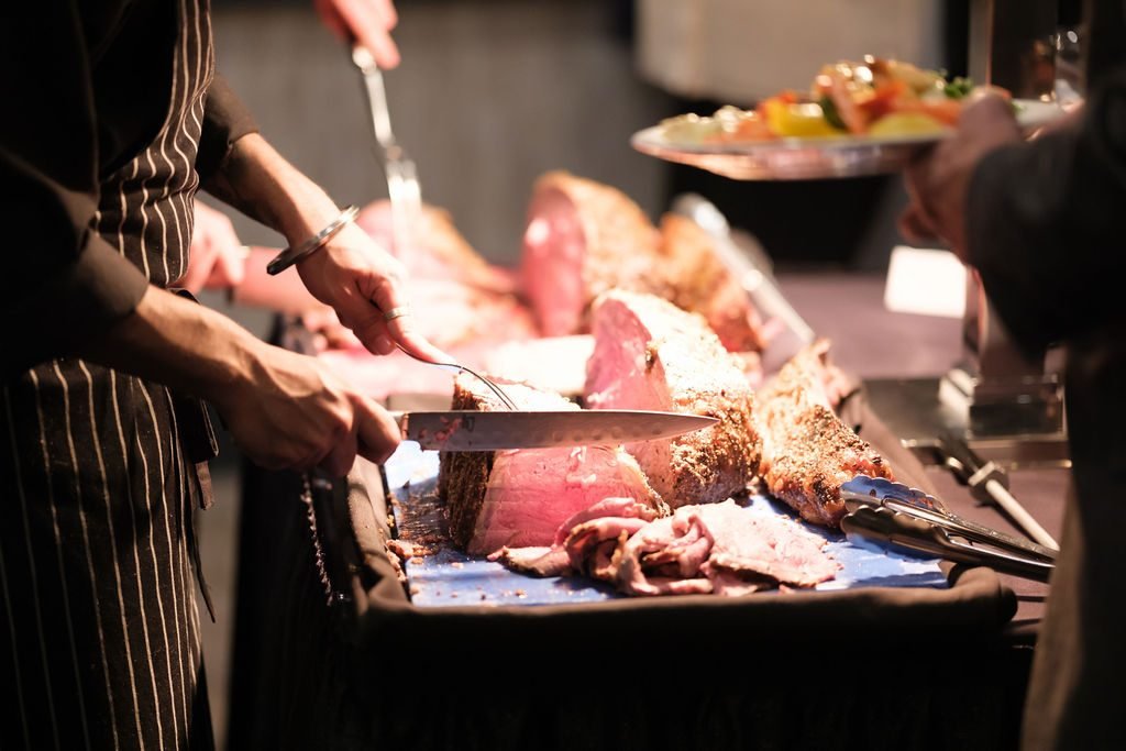 Chef carving roast beef at the catering station during a corporate banquet
