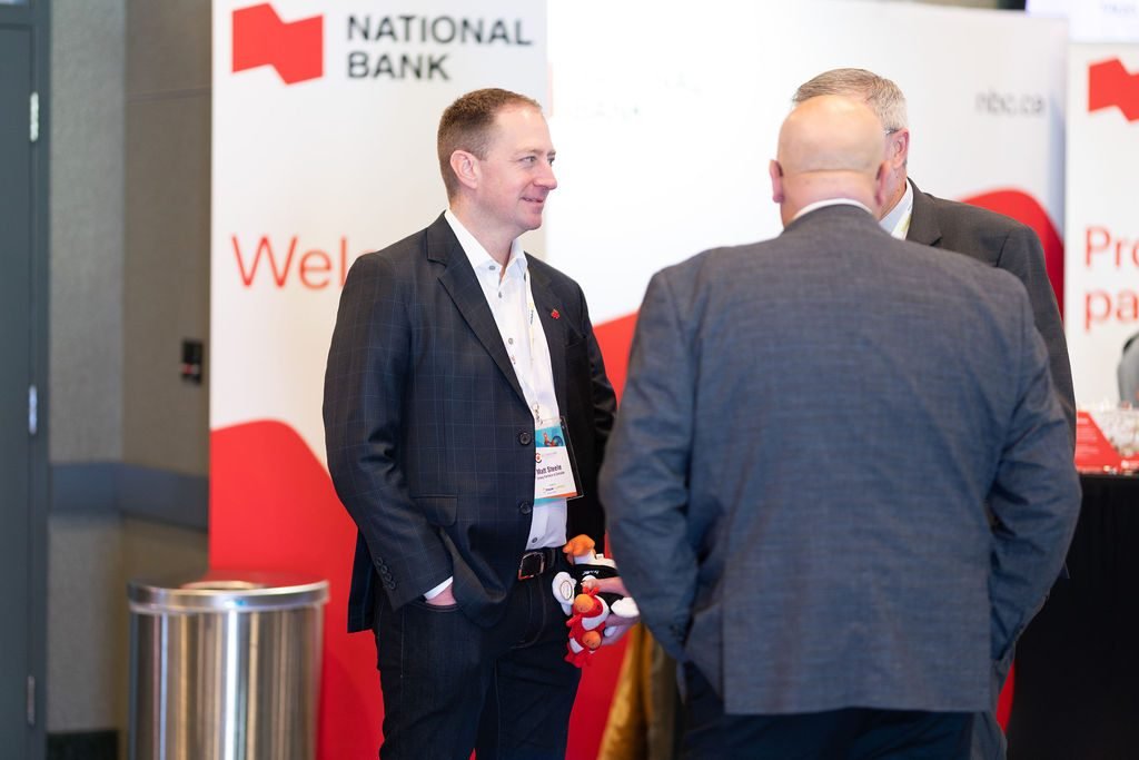 Two delegates talking in front of a sponsor branded wall at a conference reception