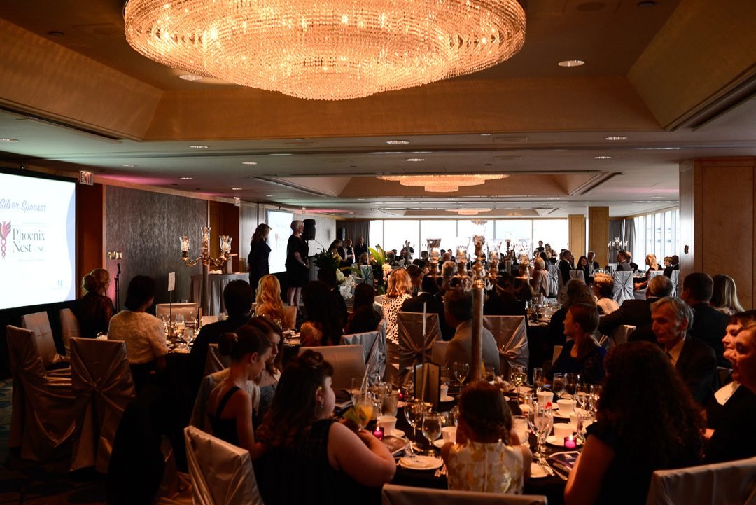 Guests seated at banquet tables during a charity fundraising gala dinner overlooking the Vancouver waterfront