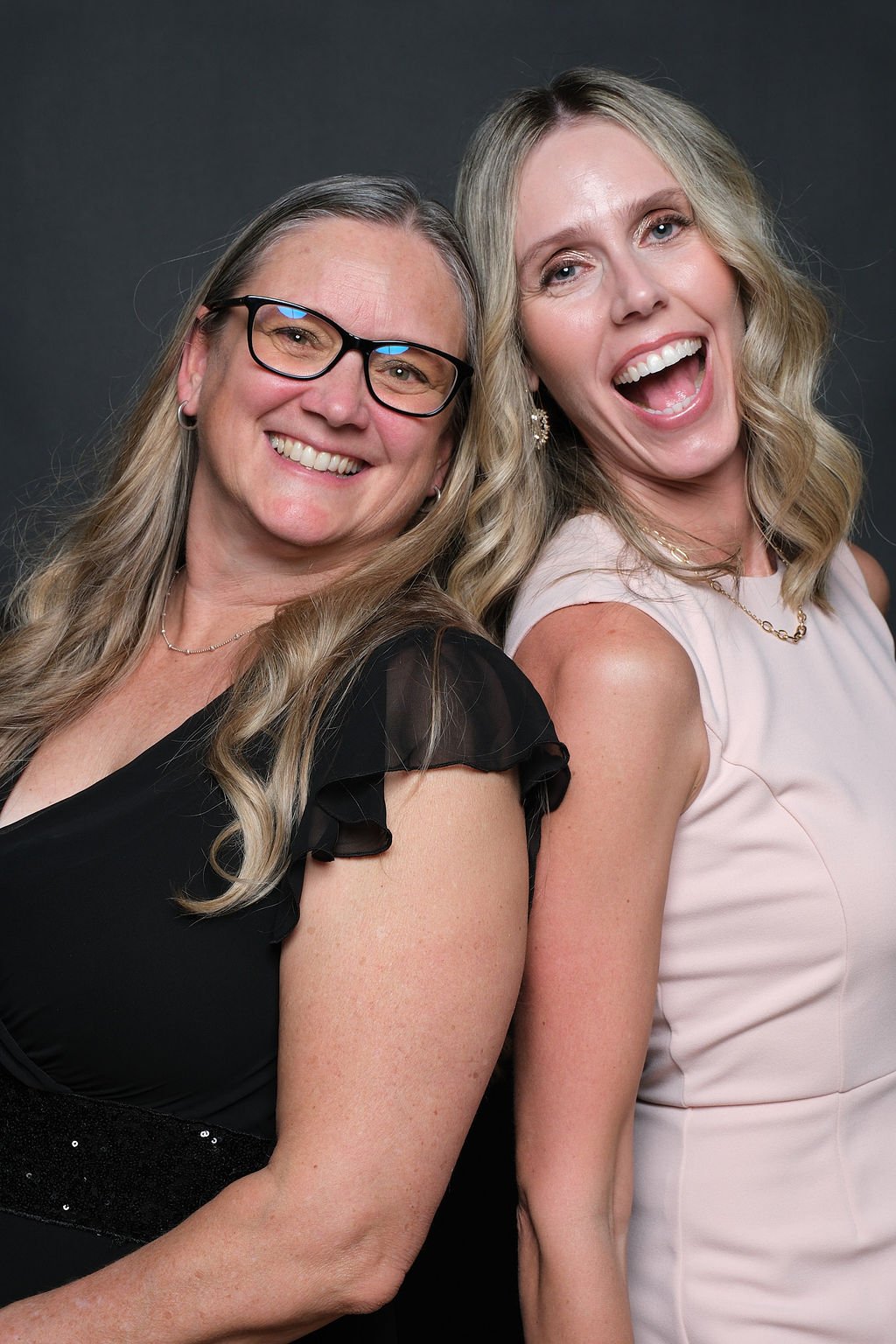 Couple laughing together in front of the dark backdrop at a charity gala