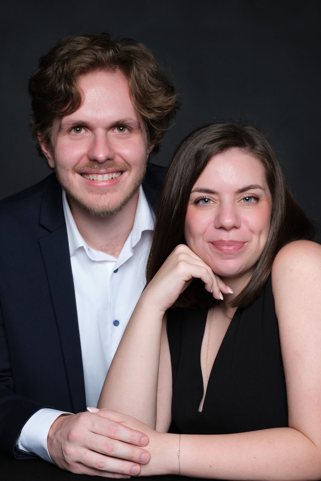 Couple leaning in for a relaxed seated portrait at an evening event