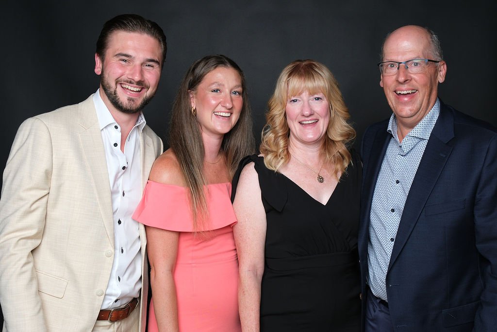 Four guests standing shoulder to shoulder for a group portrait at a gala dinner