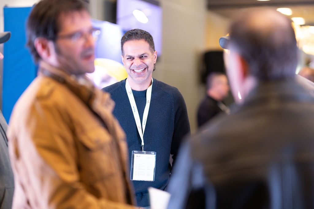 Candid photograph of a smiling delegate wearing a conference lanyard during a networking break